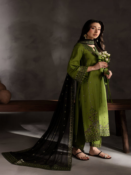 Woman in a green traditional outfit holding flowers against a dark background