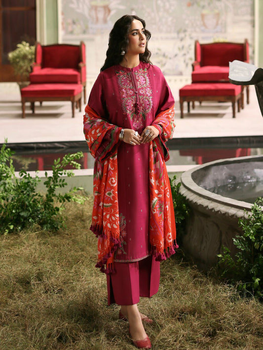 Woman in a pink and red traditional outfit standing outdoors near a pool.