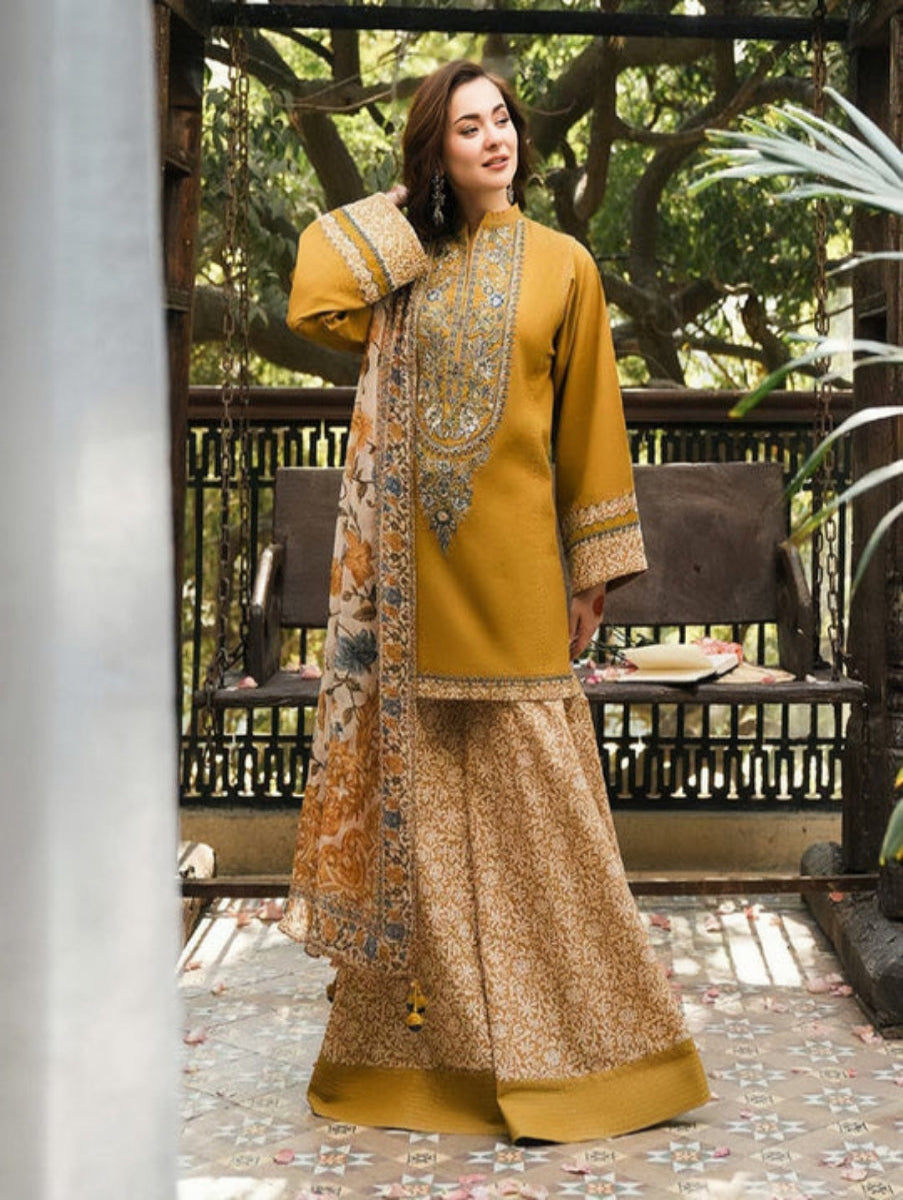 Woman in a mustard yellow traditional outfit with intricate patterns standing outdoors.