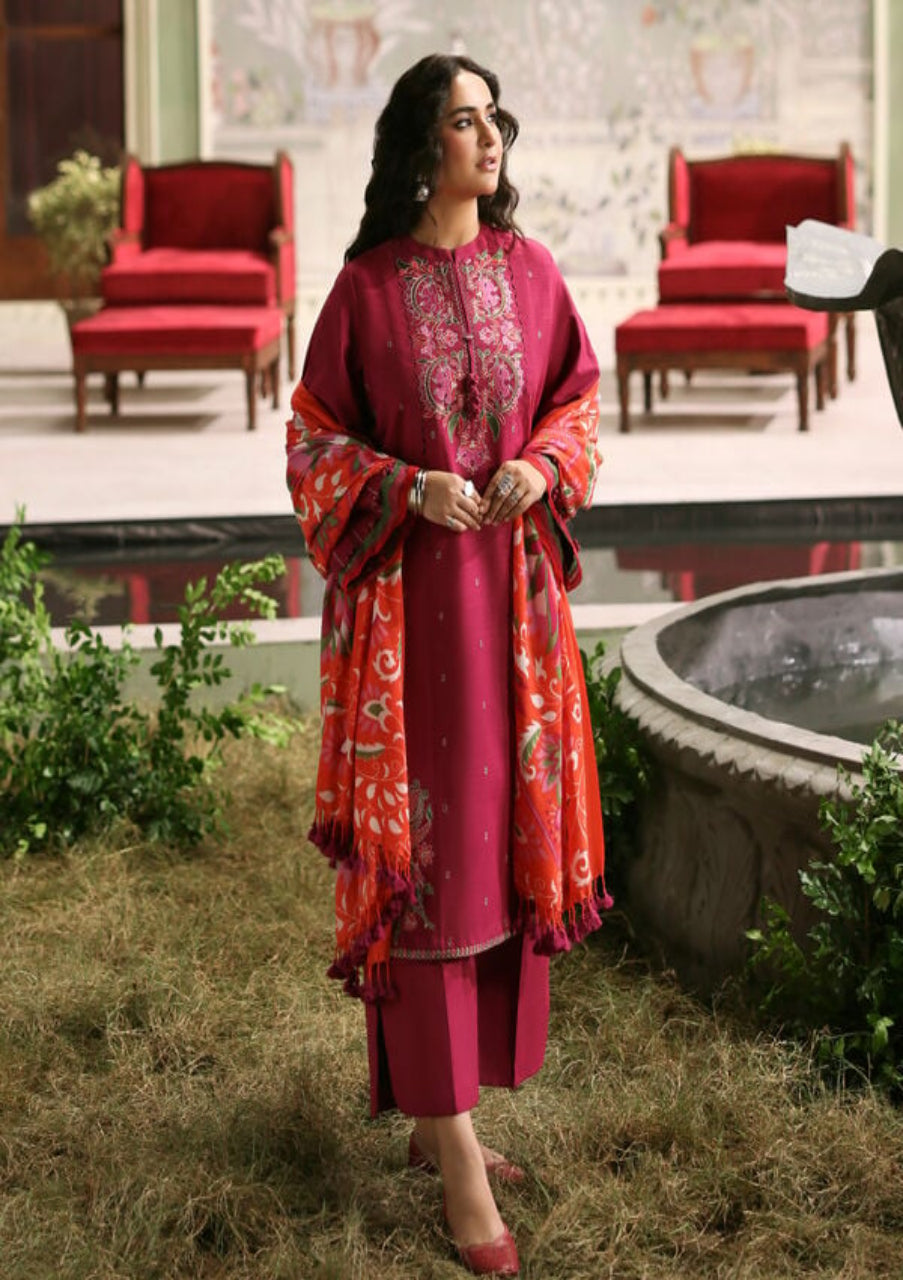 Woman in a pink and red traditional outfit standing outdoors by a pool.