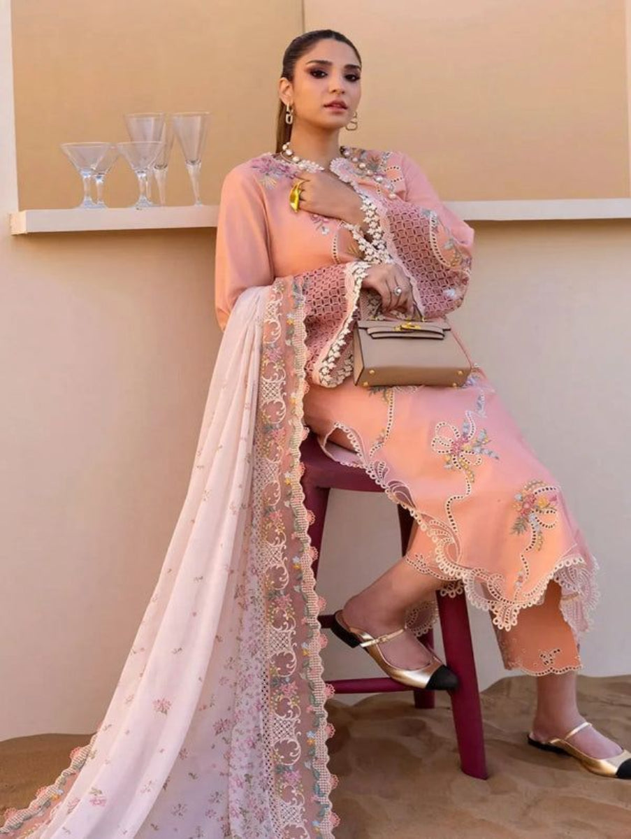 Woman in a pink traditional outfit with floral patterns sitting on a chair.