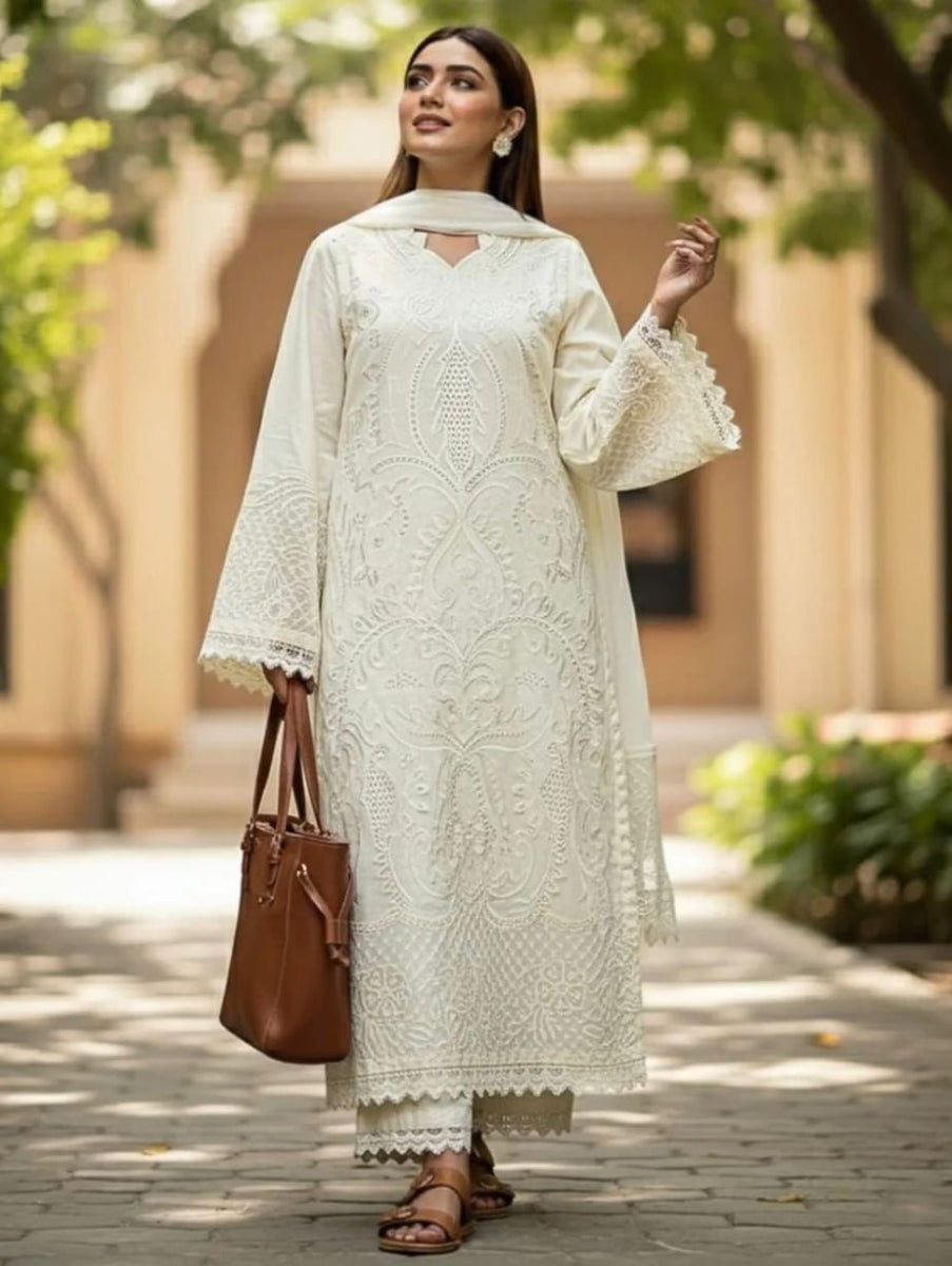 Woman in a white embroidered outfit holding a brown bag outdoors.