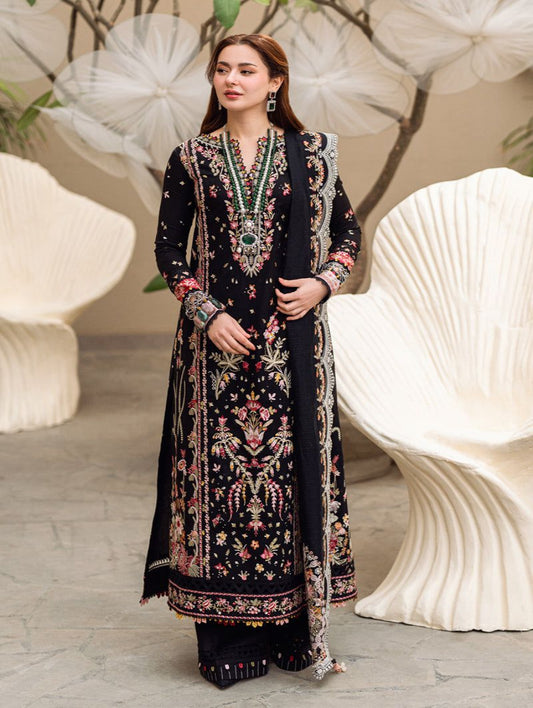 Woman wearing a black embroidered traditional outfit in an elegant indoor setting.