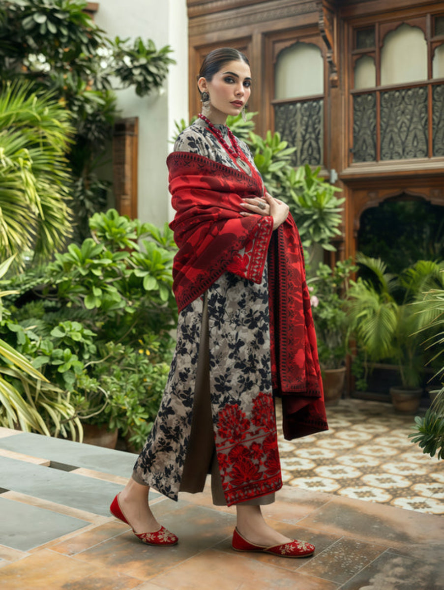 Woman in traditional outfit with red and black patterns in a garden setting