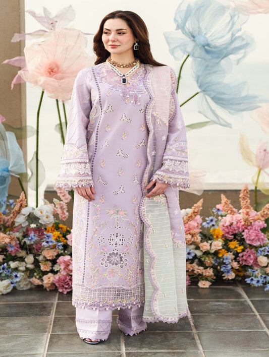 Woman in a light purple embroidered outfit standing in front of floral decorations.